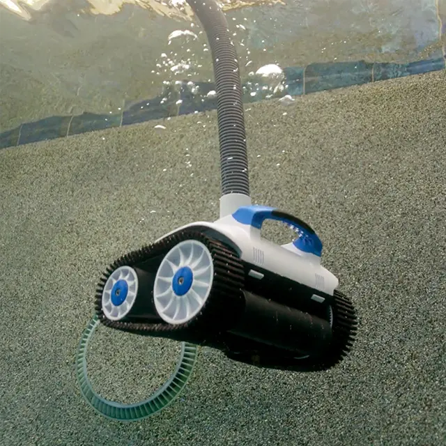 Robotic pool cleaner submerged in water, connected to a hose, and moving along a textured pool surface.